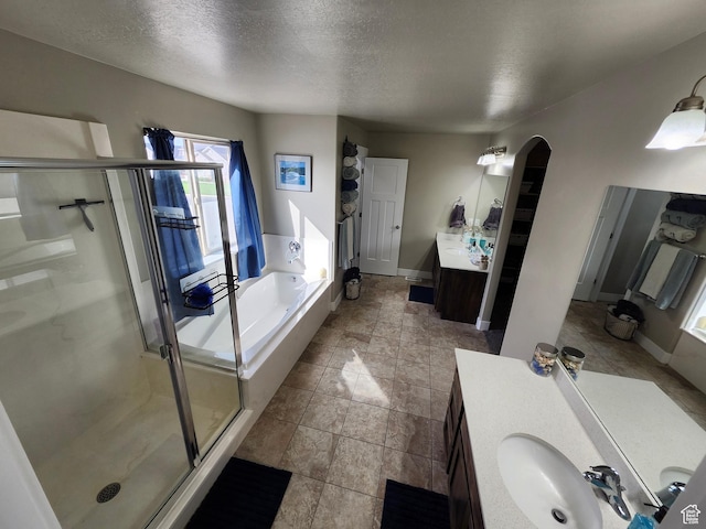 9362 N Sunnyvale Dr, Eagle Mountain, UT 84005 - full bath featuring a stall shower, two vanities, a bath, a textured ceiling, and baseboards
