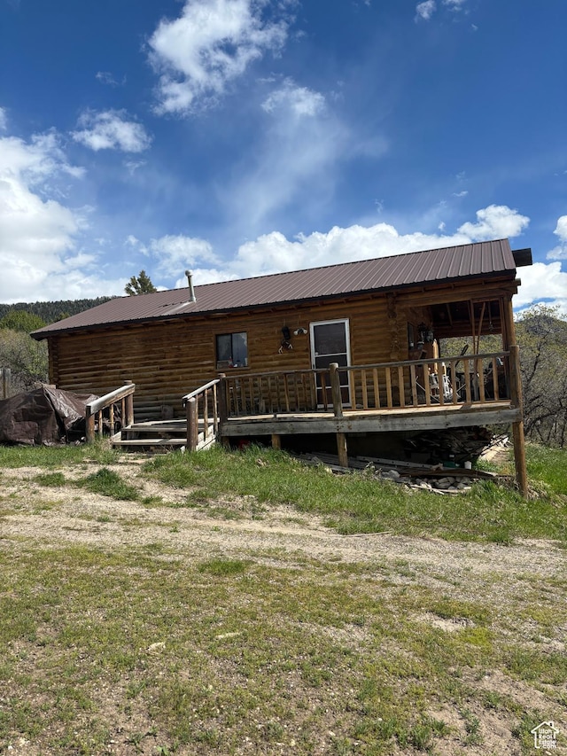 back of property with a wooden deck and metal roof