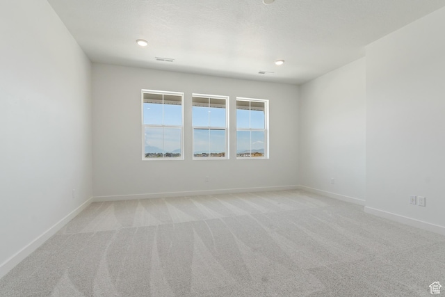 empty room featuring light carpet and baseboards