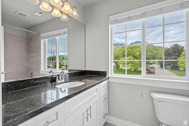 bathroom with a chandelier, baseboards, toilet, vanity, and a shower