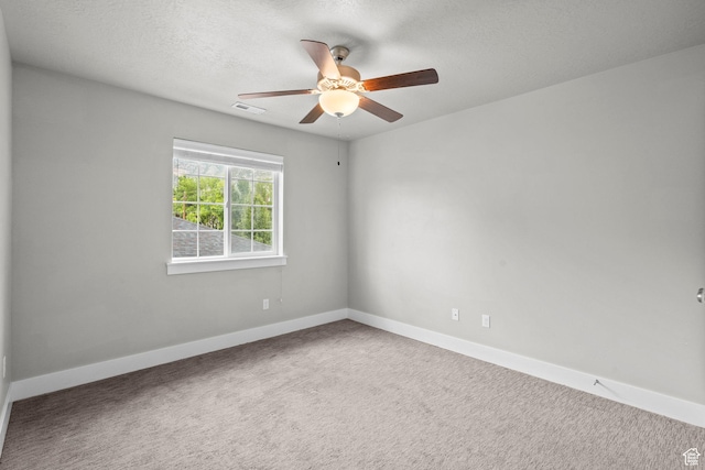 spare room with ceiling fan, carpet floors, baseboards, and a textured ceiling