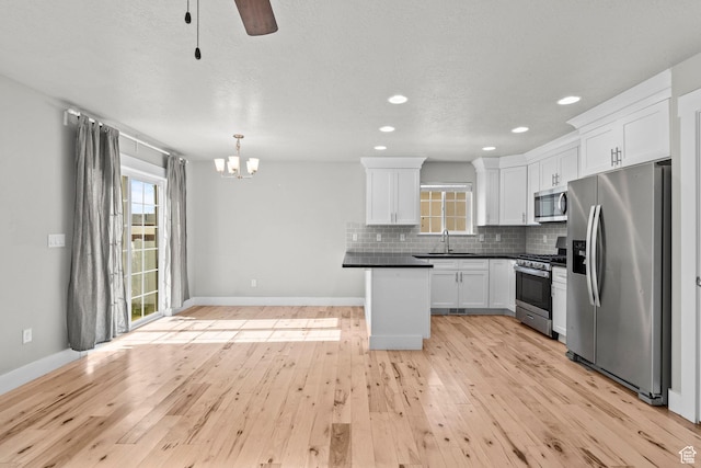 kitchen with stainless steel appliances, a sink, dark countertops, healthy amount of natural light, and recessed lighting