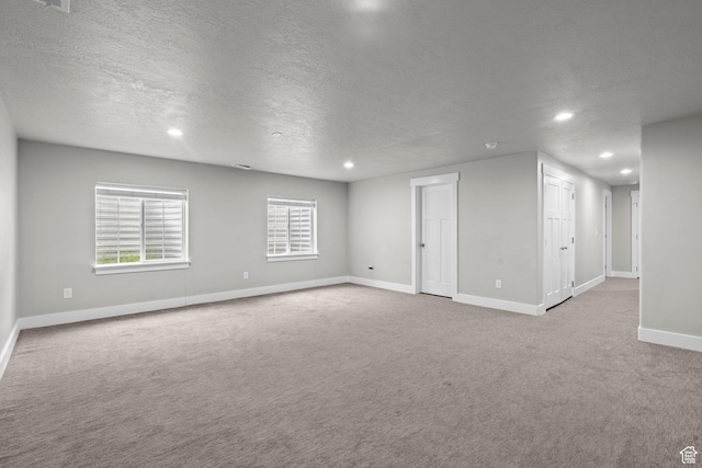 empty room featuring a textured ceiling, recessed lighting, carpet flooring, and baseboards