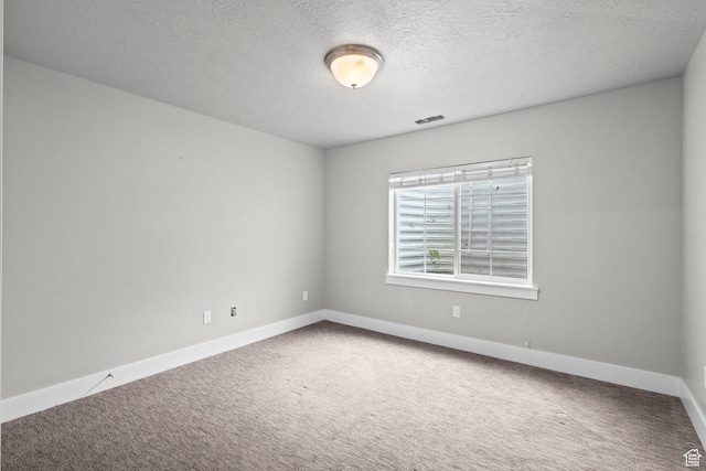 carpeted empty room featuring baseboards and a textured ceiling