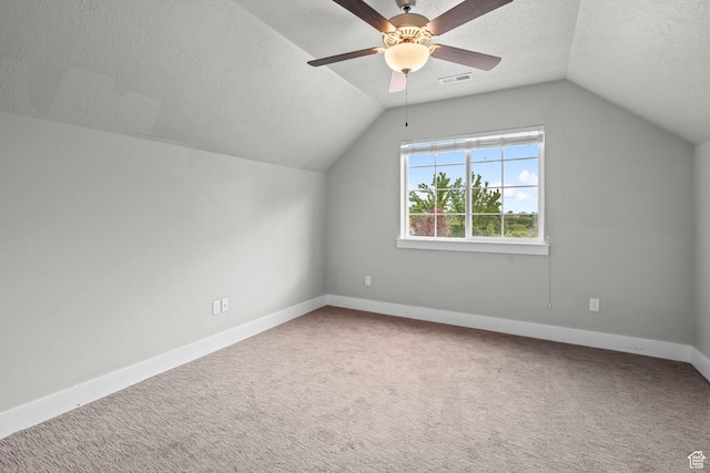 bonus room with lofted ceiling, ceiling fan, carpet flooring, baseboards, and a textured ceiling
