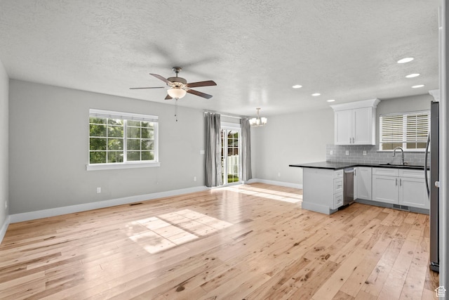 kitchen with open floor plan, appliances with stainless steel finishes, a ceiling fan, a sink, and light wood-style flooring