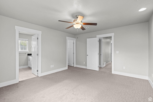 unfurnished bedroom with light carpet, baseboards, connected bathroom, and ceiling fan