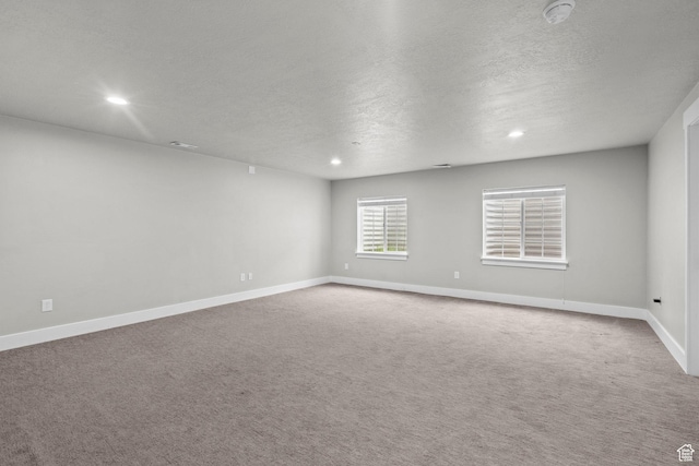 carpeted empty room featuring a textured ceiling, a smoke detector, baseboards, and recessed lighting
