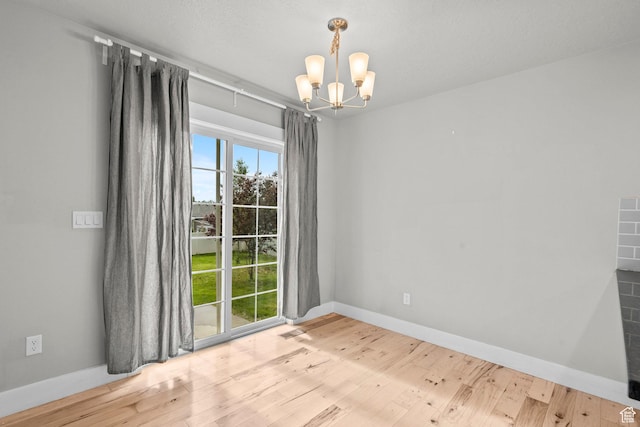 unfurnished room with a chandelier, wood finished floors, and baseboards