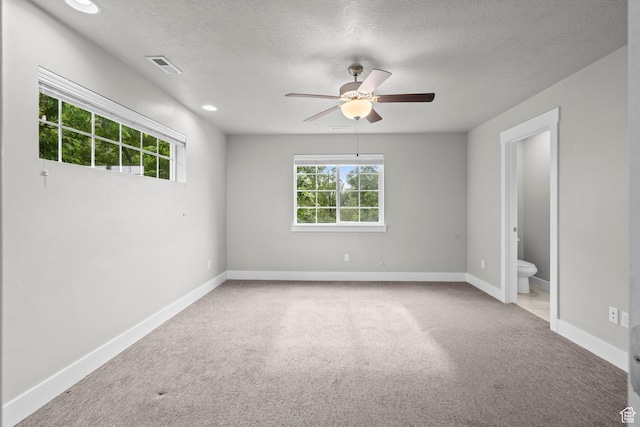 unfurnished room featuring healthy amount of natural light, a textured ceiling, ceiling fan, carpet, and baseboards