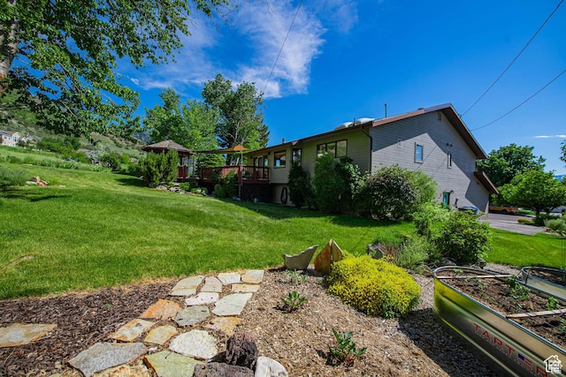 view of green lawn featuring a garden and a wooden deck
