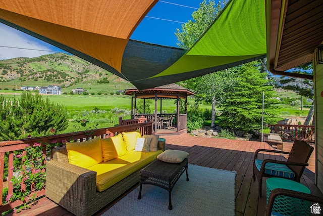 wooden deck with outdoor lounge area, a mountain view, and a gazebo
