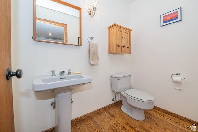 half bath featuring wood finished floors and toilet
