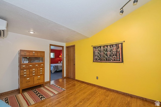 empty room with wood finished floors, a textured ceiling, and baseboards