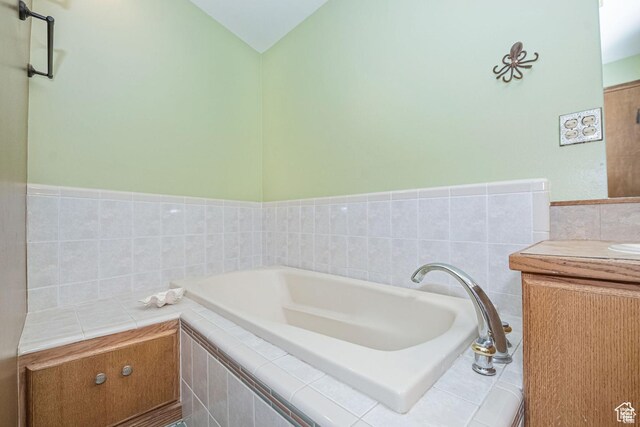 bathroom featuring a bath, vanity, and tile walls