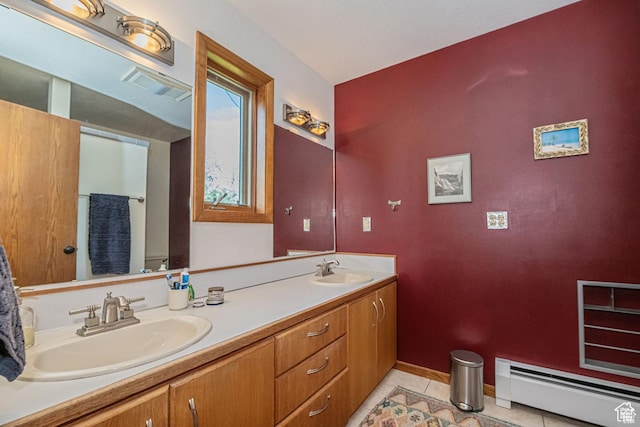 full bathroom with a baseboard heating unit, double vanity, tile patterned flooring, baseboards, and toilet