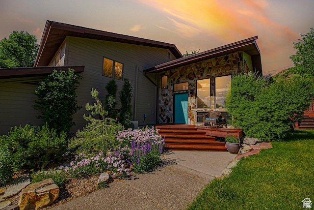 view of front of property with stone siding and a lawn