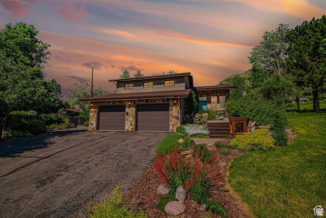 view of front of property featuring stone siding, asphalt driveway, and a garage
