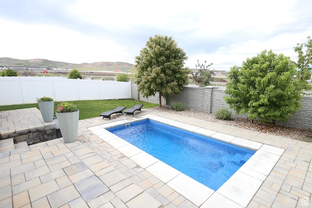 view of pool with a patio, a fenced backyard, and a mountain view