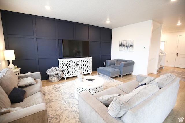 living room with light wood-style flooring, recessed lighting, and a decorative wall