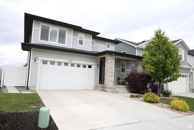 view of front of property featuring a porch, an attached garage, driveway, and fence