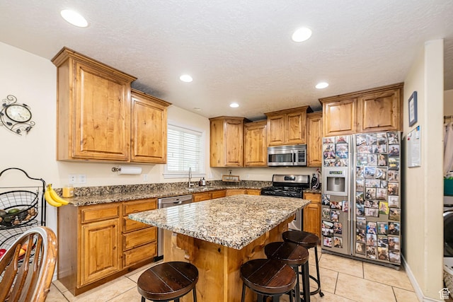 kitchen featuring stainless steel appliances, a sink, light tile patterned floors, a breakfast bar, and recessed lighting