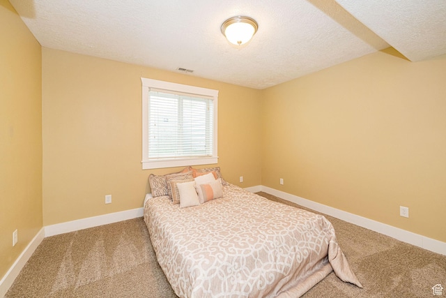 carpeted bedroom with a textured ceiling and baseboards