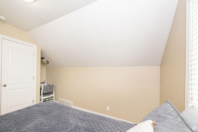 bedroom with lofted ceiling, a textured ceiling, carpet, and baseboards