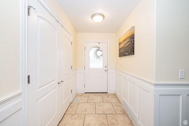 entryway with a decorative wall and wainscoting