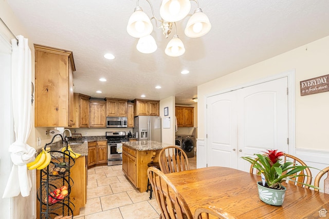 kitchen with stainless steel appliances, washer and dryer, a chandelier, a center island, and recessed lighting