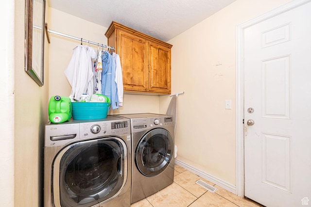 washroom with washing machine and clothes dryer, light tile patterned floors, cabinet space, and baseboards