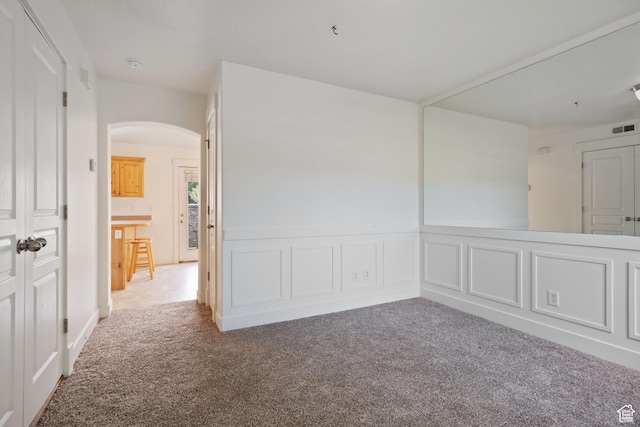 381 S State St E Unit 12, Provo, UT 84606 - carpeted empty room featuring arched walkways, a wainscoted wall, and a decorative wall