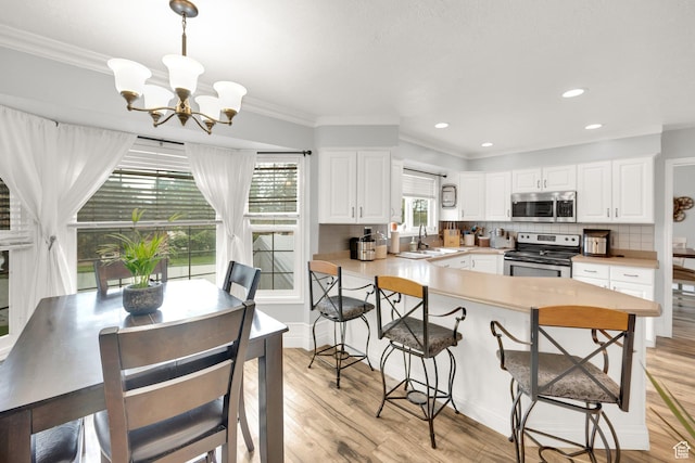 13856 S Cromwell Ln E, Draper, UT 84020 - kitchen featuring stainless steel appliances, a sink, a chandelier, a breakfast bar, and light wood-style floors