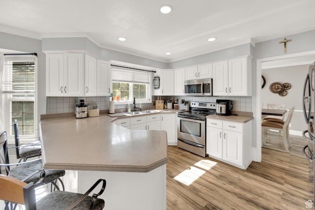 13856 S Cromwell Ln E, Draper, UT 84020 - kitchen with appliances with stainless steel finishes, a sink, a peninsula, a kitchen bar, and crown molding