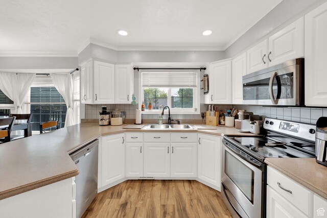 13856 S Cromwell Ln E, Draper, UT 84020 - kitchen with stainless steel appliances, a sink, light wood-type flooring, crown molding, and tasteful backsplash