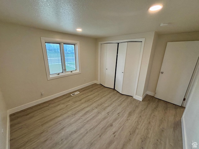 unfurnished bedroom with light wood-type flooring, baseboards, recessed lighting, a closet, and a textured ceiling
