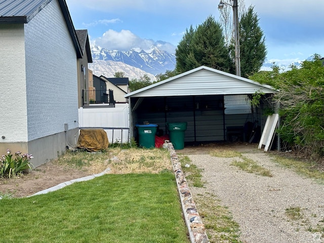 view of outbuilding featuring dirt driveway, a mountain view, and a detached carport