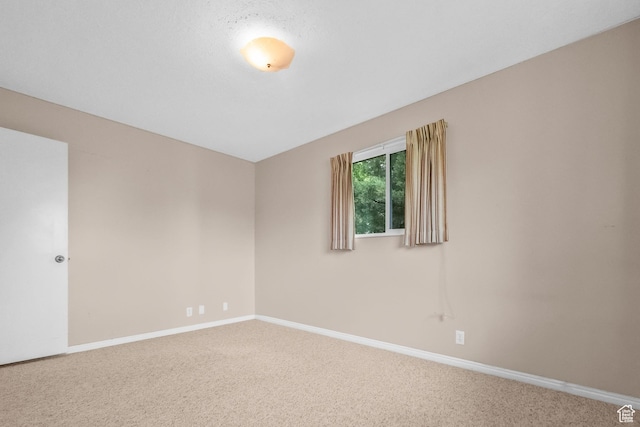 carpeted empty room featuring baseboards