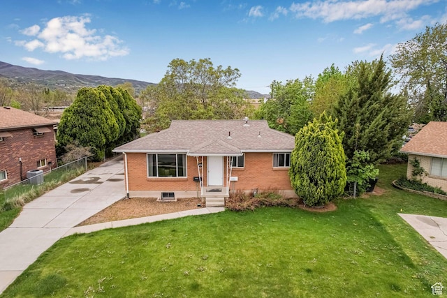 view of front of home featuring brick siding, central AC unit, a shingled roof, and a mountain view