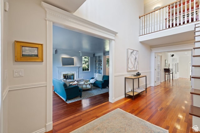 living room featuring wood finished floors, a glass covered fireplace, and baseboards