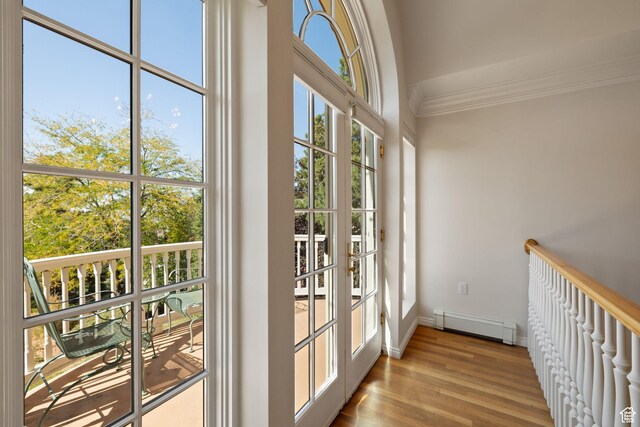 entryway featuring a baseboard heating unit, ornamental molding, baseboards, and wood finished floors