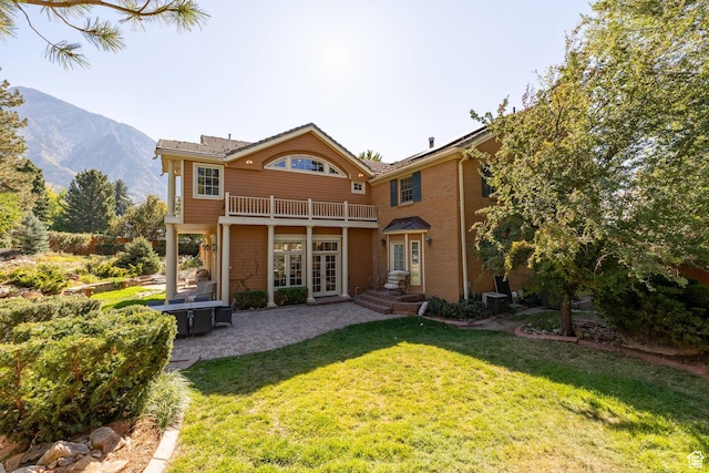 rear view of house with french doors, a balcony, a yard, a patio area, and a mountain view