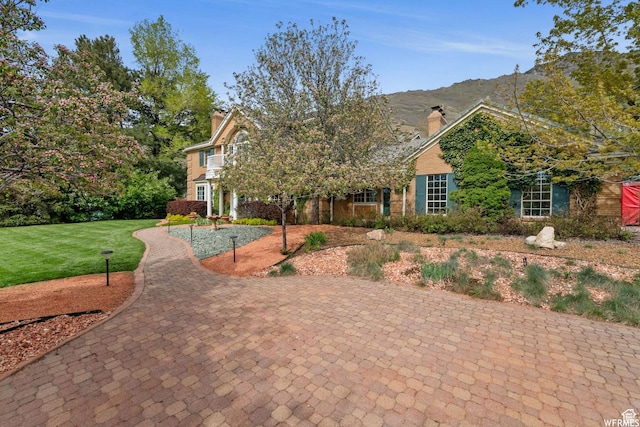 view of front of property with a chimney, a mountain view, and a front lawn