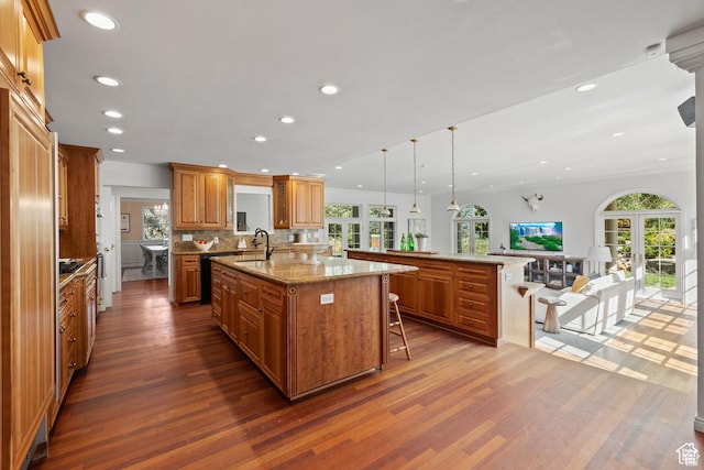 kitchen featuring a large island with sink, dark wood-style flooring, a breakfast bar, brown cabinetry, and recessed lighting