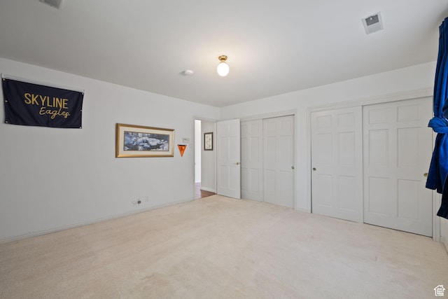 unfurnished bedroom with two closets and carpet flooring