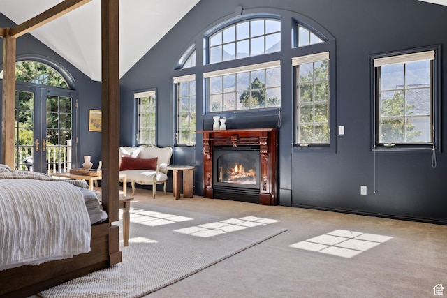 carpeted bedroom featuring a glass covered fireplace, multiple windows, french doors, beam ceiling, and high vaulted ceiling