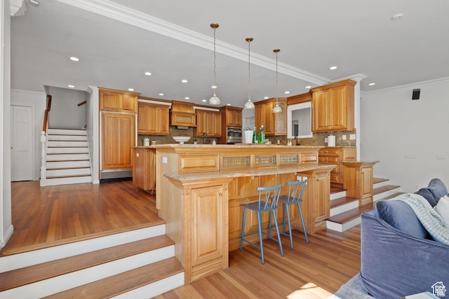 kitchen featuring light wood finished floors, open floor plan, custom range hood, decorative backsplash, and recessed lighting