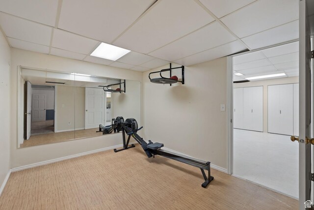 workout room featuring a paneled ceiling, baseboards, and carpet