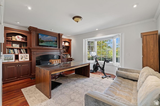 home office featuring light wood-style floors, a glass covered fireplace, ornamental molding, recessed lighting, and baseboards