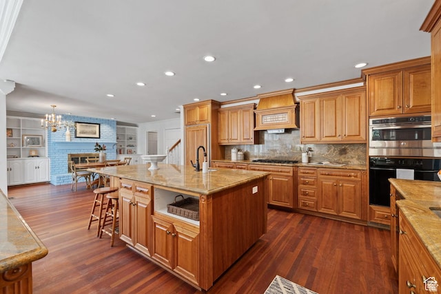 kitchen featuring custom range hood, gas cooktop, double oven, a breakfast bar, and dark wood-style floors